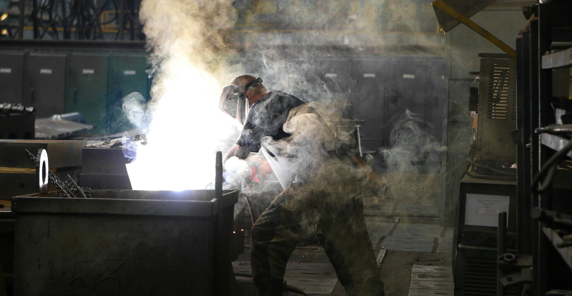 A skilled welder working with intense sparks and smoke in an industrial workshop, showcasing safety and precision.
